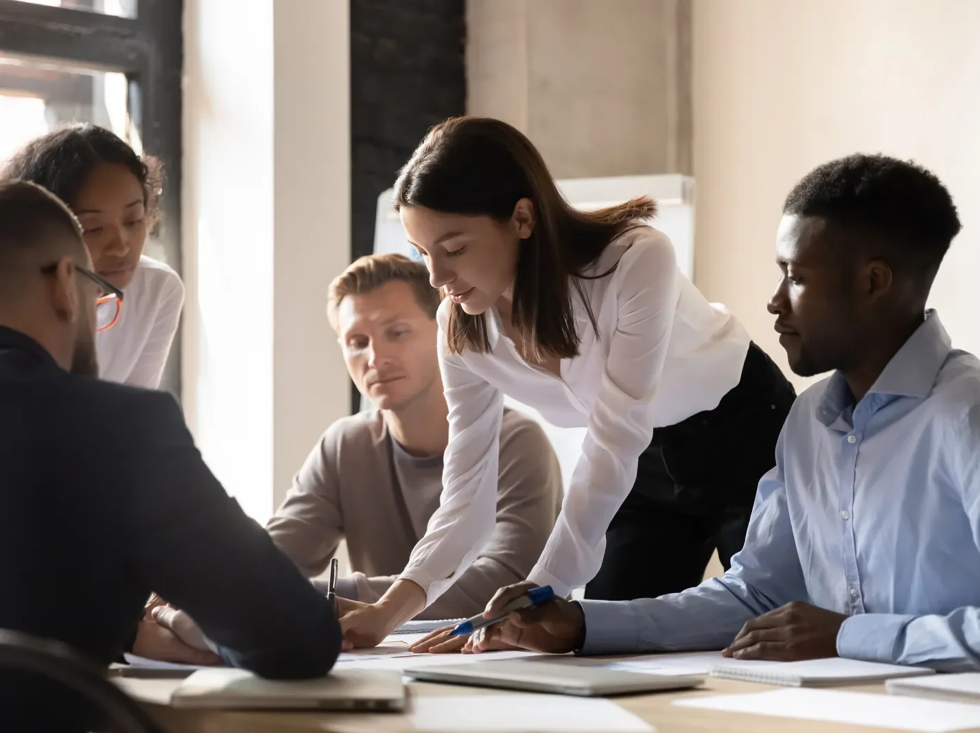 People meeting around an office conference table reviewing documents